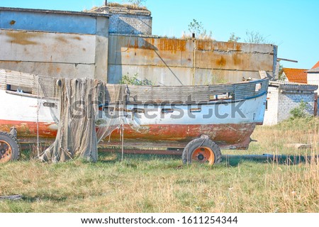 An old peeling fishing boat stands on the shore. A fishing net hangs on a boat. The texture of the old wood.