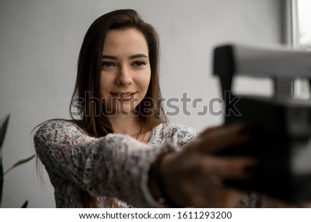Smiling young brunette woman takes photographs selfie portrait with old photo camera