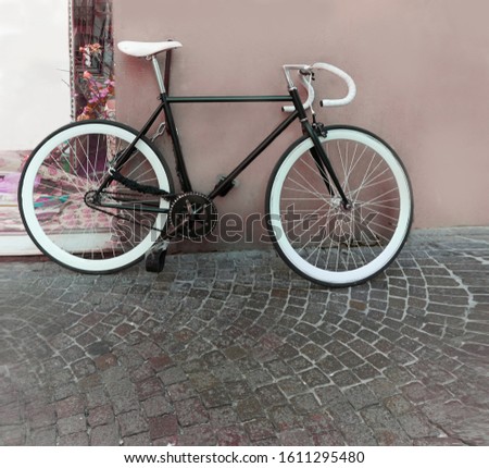Black hipster bike with white tires leaning against the wall                                                               
