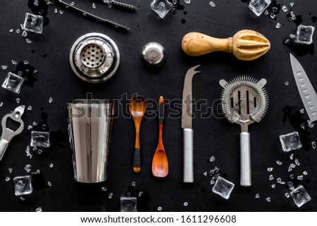 Bartender equipment set with shaker and stainer and ice cubes on black background top-down pattern
