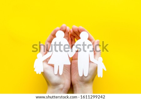 Live insurance concept. Family silhouette on palms on yellow background top-down