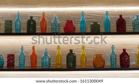multi-colored bottles of different shapes stand in a row on the shelves