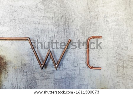 volume iron inscription WC on a white-gray wall with scratches, design