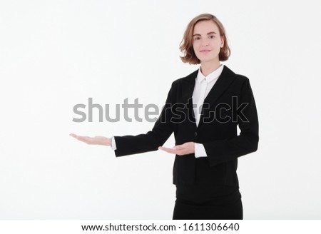  Young Caucasian business woman in black suit pointing to presenting something on her side, isolated on white background with copy space, business concept.
