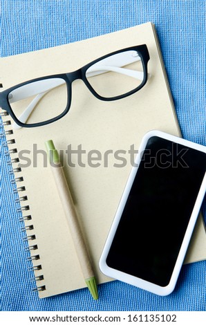 Office supplies Notebook paper smartphone and glasses . 