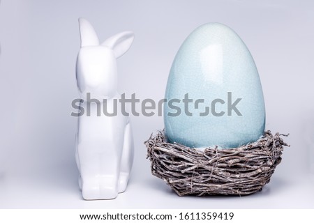 easter bunny figuer next to a mint green easter egg in a small nest made of twigs, creative easter and spring decoration 2020, trend colors on white isolated background