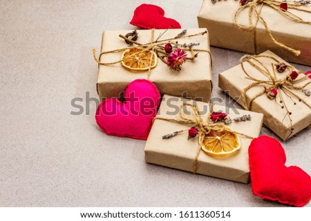 Zero waste gift concept. Valentine Day or Birthday eco friendly packaging. Festive boxes in craft paper with different organic decorations. Stone concrete background, copy space