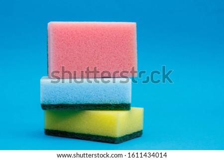 Multicolored sponges for cleaning and washing dishes on a blue background. Space for text