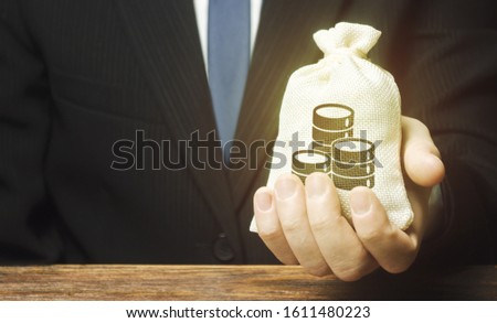 Businessman is holding a money bag in front of him. Provision money credit, grant. Project financing. Donations. Financial social assistance. Payment purchases, profits dividends. Business investment Royalty-Free Stock Photo #1611480223
