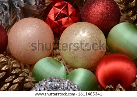 Christmas ornaments and decorative pine cones sit in a basket.