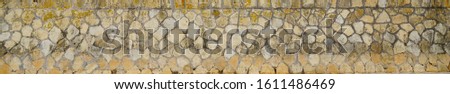 long Panorama in Old beige gray wall coarse many small natural stones