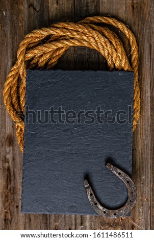 Black chalk board with horseshoe and lasso on wooden background