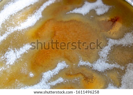 A close up view of white sugar dissolving in a pan and turing into caramal 