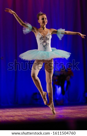 Young girl ballerina in a light blue dress tutu dancing performance of a ballet on stage in a theater