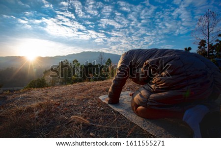 Man kneeling down and praying at sunset on mountain. christian  concept.