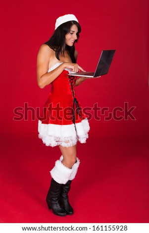 Woman In Santa Claus Costume Working On A Laptop Over Red Background