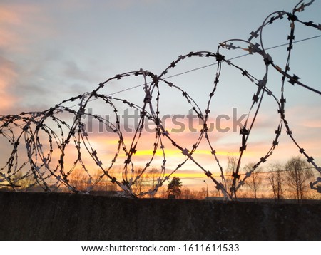 sunset behind a barbed wire fence