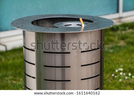 metal urn for mixed garbage and cigarette butts on the street of the city. sticking a cigarette butt extinguished in the garbage, separate collection of waste Royalty-Free Stock Photo #1611640162