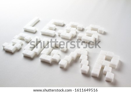 "Less sugar" spelled with pixel art letters made out of sugar cubes on a white background