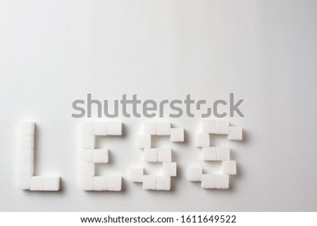 "Less" spelled with pixel art letters made out of sugar cubes on a white background