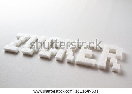 "Sugar" (Zucker in German) spelled with pixel art letters made out of sugar cubes on a white background