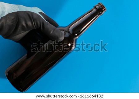 The man holds an empty bottle in his hand without a cork or label