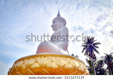 White Buddha statue and blue sky background at Paknam Lemson temple in Chumphon province, southern Thailand. Beautiful Buddha statue in Asia.