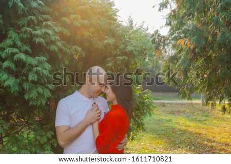 Happy lovers in the park at thuja in autumn sunny weather.