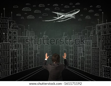 Young businessman sitting in an office chair and looking on a sketched cityscape drawing on a chalkboard