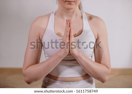 Young sporty attractive woman practicing yoga, meditating in yoga pose, working out, wearing sportswear, indoor full length, light yoga Studio