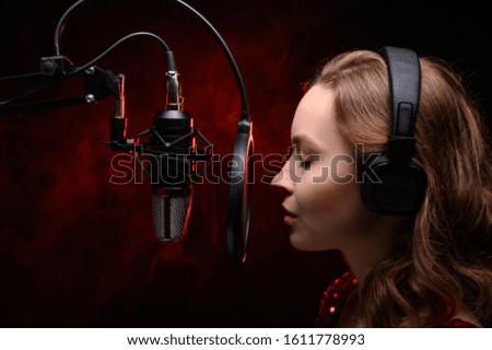 Vocalist singing in studio. School and vocals. Against the backdrop of red smoke.