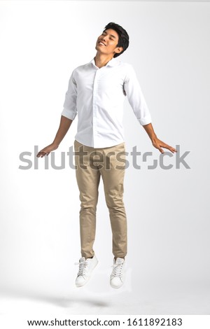 Full body portrait of young Asian man in white casual shirt pose like standing in the air with impress  happiness and sweetly close eyes. Studio shot on white background.  Royalty-Free Stock Photo #1611892183