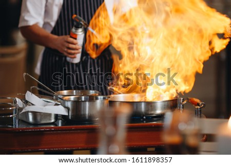 The chef prepares food in front of the visitors in the restaurant close up.