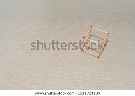 Matchstick cube laying on wood grain tabletop.