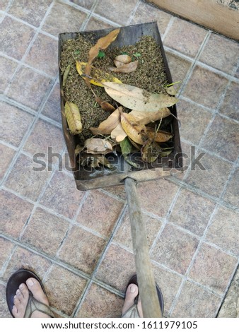 Blown leaf in garbage basket on concrete floor