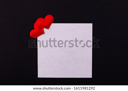 White sheet for notes with two red hearts on a black background