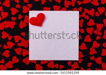 White sheet for notes with a red heart. Background of small red hearts on a black background