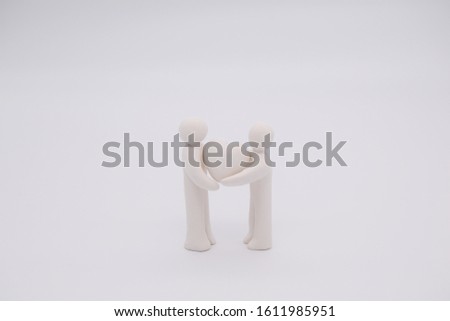 Concept image of clay doll representing clay couple, man, woman and their heart on white background. Happy doll of white color and simple style. Horizontal position.