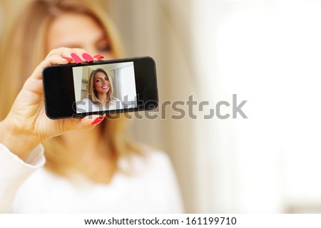 Young woman making self-photo on smartphone