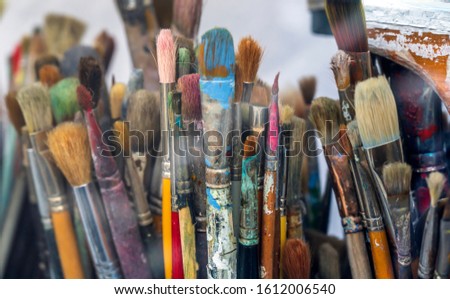 Various art brushes of different thicknesses and shapes for working with oil or acrylic paint stand in the artistâ€™s workshop waiting for the creation of the next amazing painting masterpiece