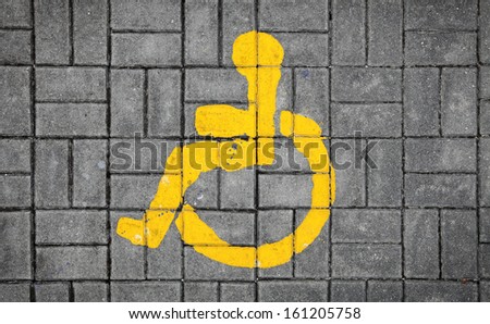 A wheelchair disabled man symbol imprint on a grungy brick pavement. 