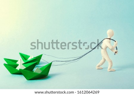 man pulls on the ropes four paper green boats. concept of business, success, hard work.
