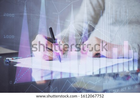 Hand taking notes in notepad. Forex chart holograms in front. Concept of research. Multi exposure