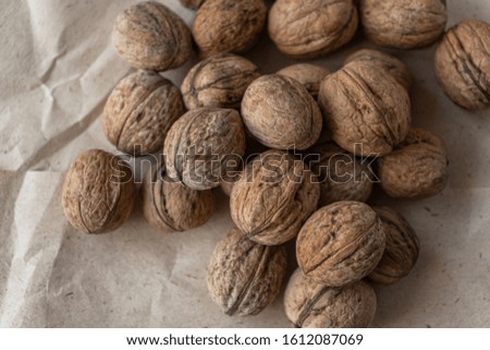 A handful of inshell walnuts on old crumpled kraft paper, brown background, warm beige picture, Top view, copyspace