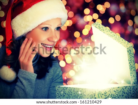 happy woman in a Christmas cap opens the magic box gift