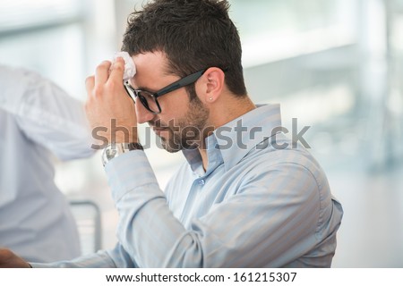 Tired business man with glasses wiping his forehead Royalty-Free Stock Photo #161215307