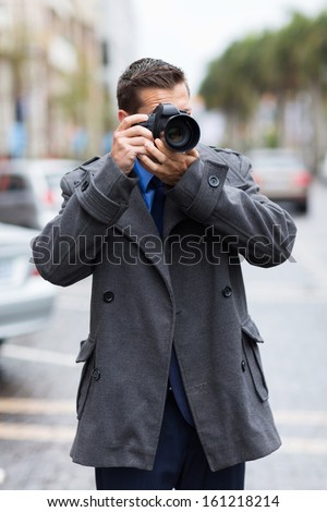 professional male photographer taking street photos in the city in a raining day