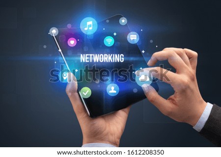 Businessman holding a foldable smartphone with NETWORKING inscription, social media concept