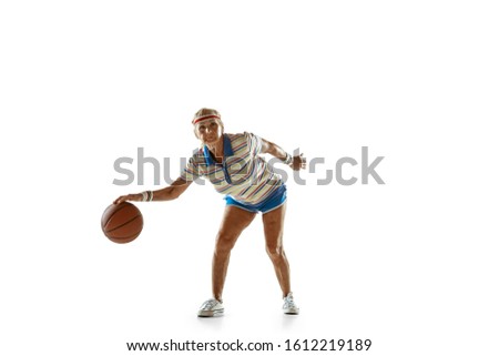 Energy. Senior woman wearing sportwear playing basketball on white background. Caucasian female model in great shape stays active. Concept of sport, activity, movement, wellbeing, confidence