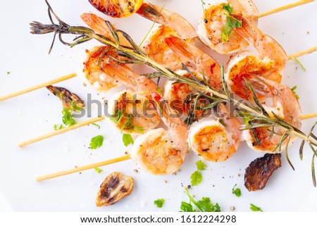 grilled shrimp on skewers. Grilled seafood on skewers with spices, herbs and lemon. delicious prawn. White plate. White background